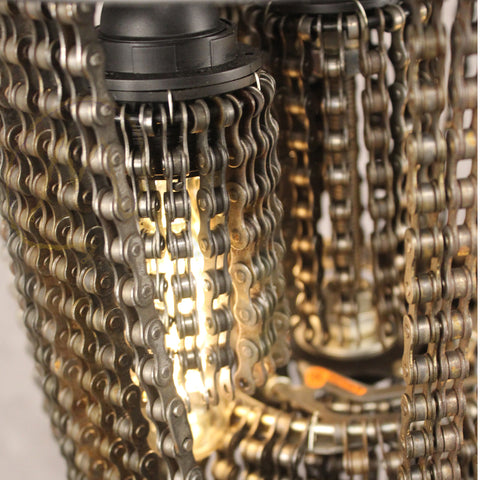 Fietskunstkroonluchter gemaakt van fietskettingen met warme gloeilampen die het ingewikkelde ontwerp verlichten