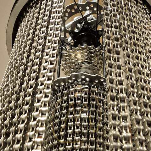 Een close-up van een metalen ketting verweven met een gloeilamp, die het unieke ontwerp van de fietskettinglamp laat zien.