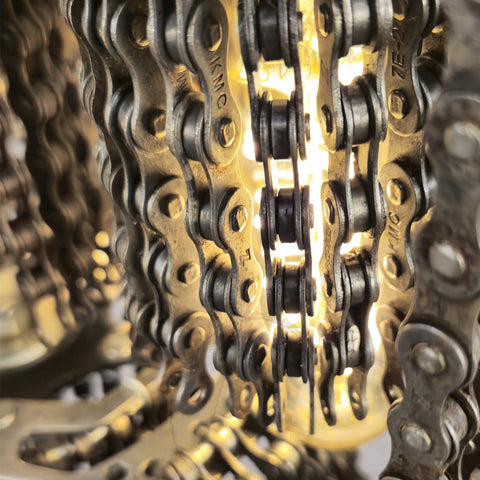 Close-up van een chandelier met kettingen, die de esthetiek van een fietswiel lamp weerspiegelt.