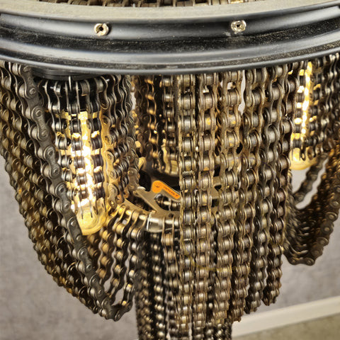Detailopname van een kroonluchter met kettingen, met een ontwerp dat doet denken aan een fietswiel lamp.
